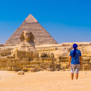 A young man walking towards the Great Sphinx of Giza and in the background the pyramid of Khafre,